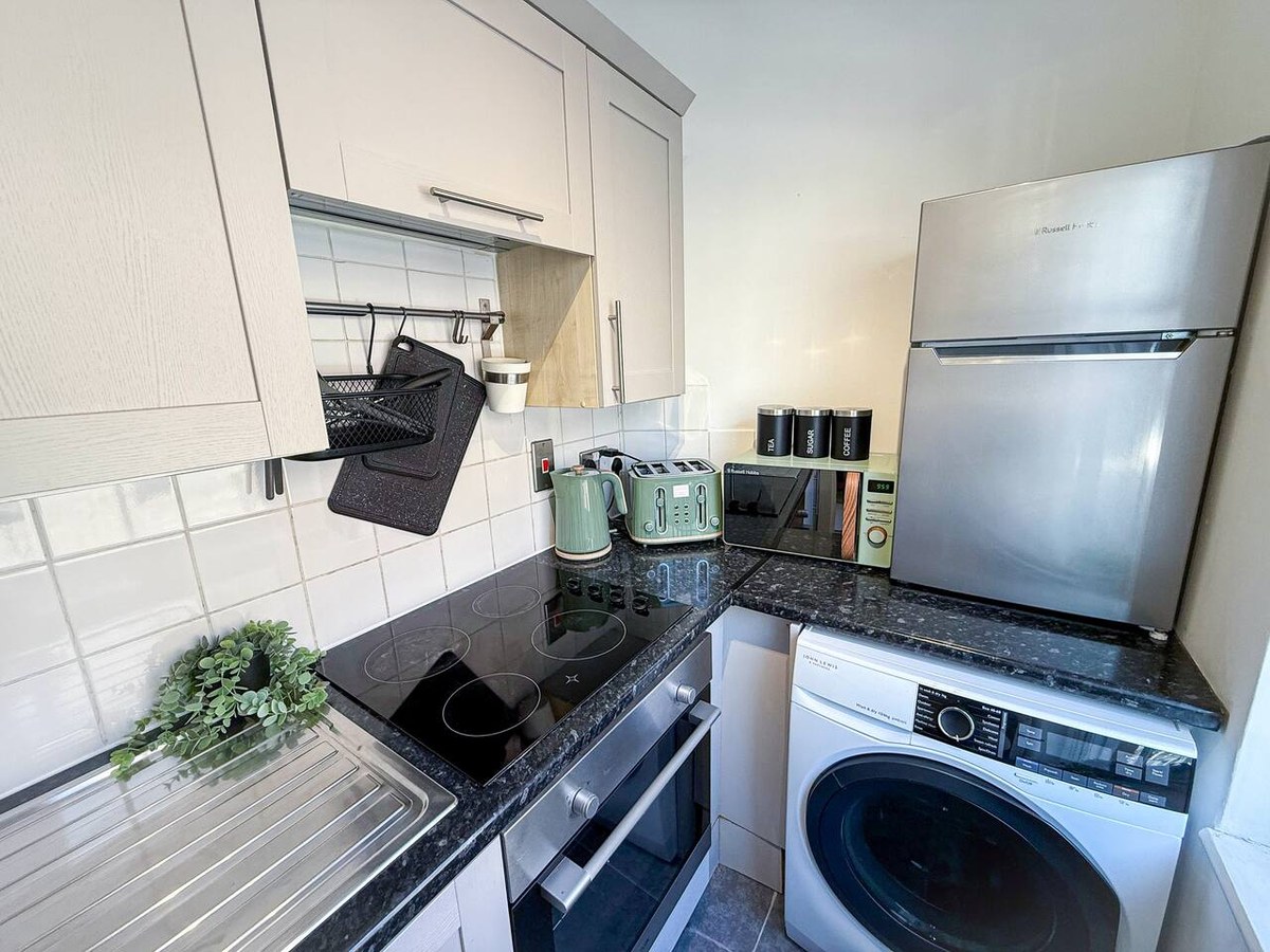 Kitchen with a hob and laundry machines in Hackney